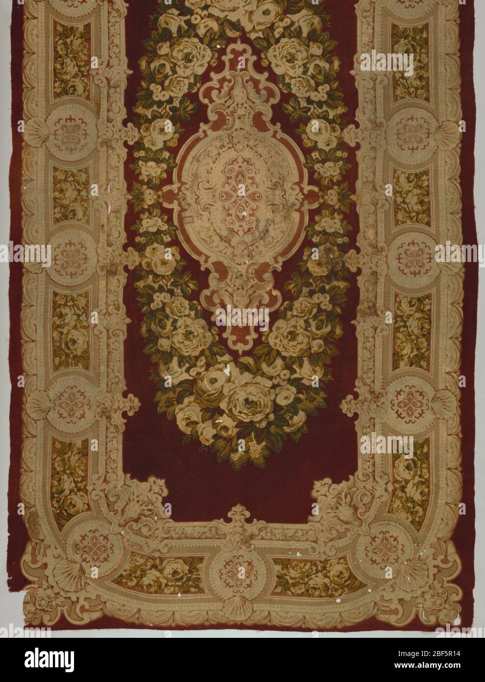 Tischabdeckung. Bedruckter rechteckiger Tischbezug aus Wolle. Feld: Medaillon umgeben von einem Kranz von Blumen auf kastanienbraunen Feld. Bordüre: Aufwändig umrandete Wiederholung von floralem Band und Medaillon, die die Ecken umrunden. Beachten Sie Hirschkopf an der Innenseite Rand an den Ecken. Dunkle dunkle Farben. Stockfoto