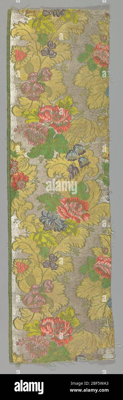 Textil. Blüten und Akanthus Blätter in Gold auf silbernem Hintergrund. Blüten rot, blau, violett und grün schattiert. Fragment hat Besatz von Seidenstreifen. Stockfoto