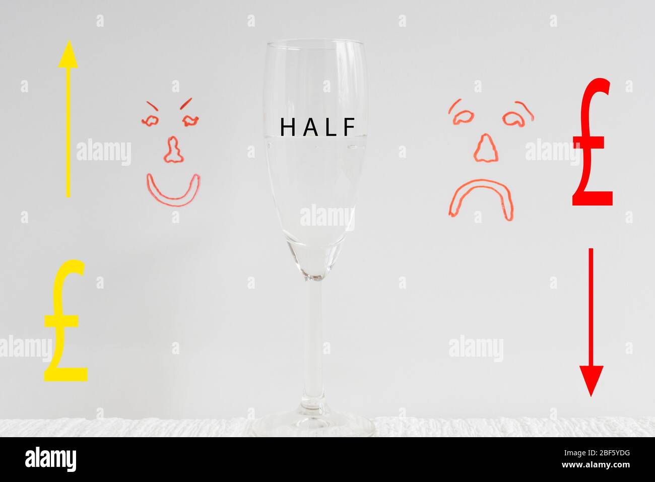 Ein Weinglas, halb voll mit gezeichneten Pfund Zeichen, traurig und glücklich Gesichter im Hintergrund Darstellung Konzept von Glas halb voll oder Glas halb leer. Stockfoto