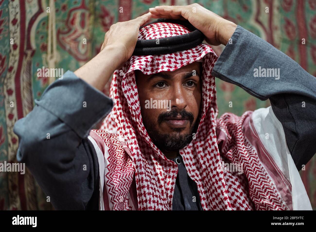 Beduinenmann mit traditionellem Kopftuch schaut sich in seinem Smartphone  in der saudischen Wüste, Saudi-Arabien, an Stockfotografie - Alamy
