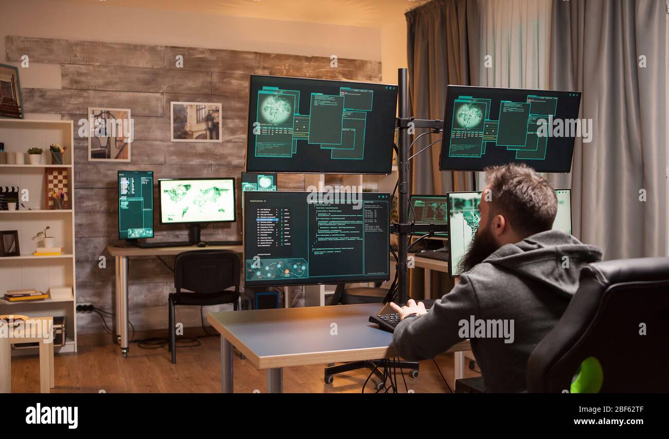 Bärtiger Hacker in einem Raum voller Computer, um die Sicherheit der Regierung anzugreifen. Stockfoto