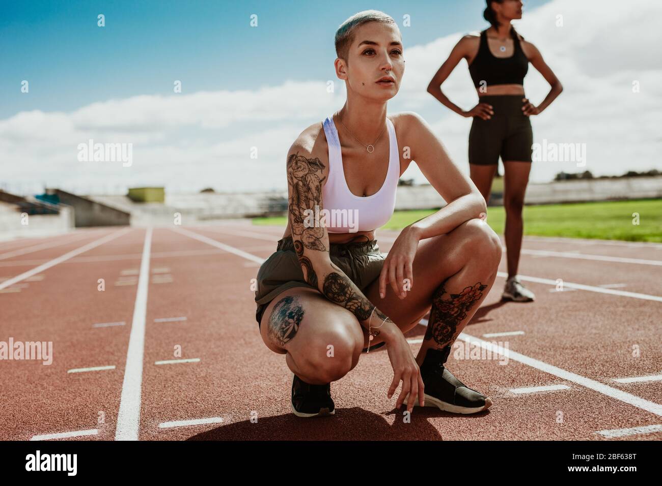 Sportlerinnen auf der Laufstrecke vor dem Rennen. Junge Läuferinnen bereiten sich auf das Rennen im Stadion vor. Stockfoto