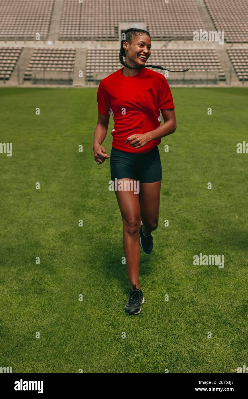 Lächelnde Fußballspielerin auf dem Spielfeld. Frau im Uniformtraining auf dem Fußballplatz. Stockfoto
