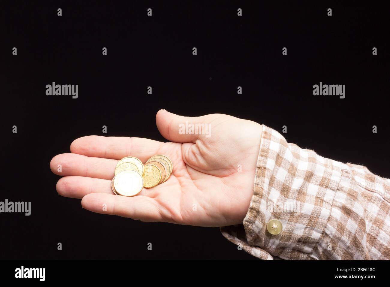Almosen in der Hand eines weißen Erwachsenen, Bettler um Geld bitten. Münzen in der Hand eines Erwachsenen, um kleine Einkäufe in Nachbarschaftsläden zu tätigen. Pennies in h Stockfoto