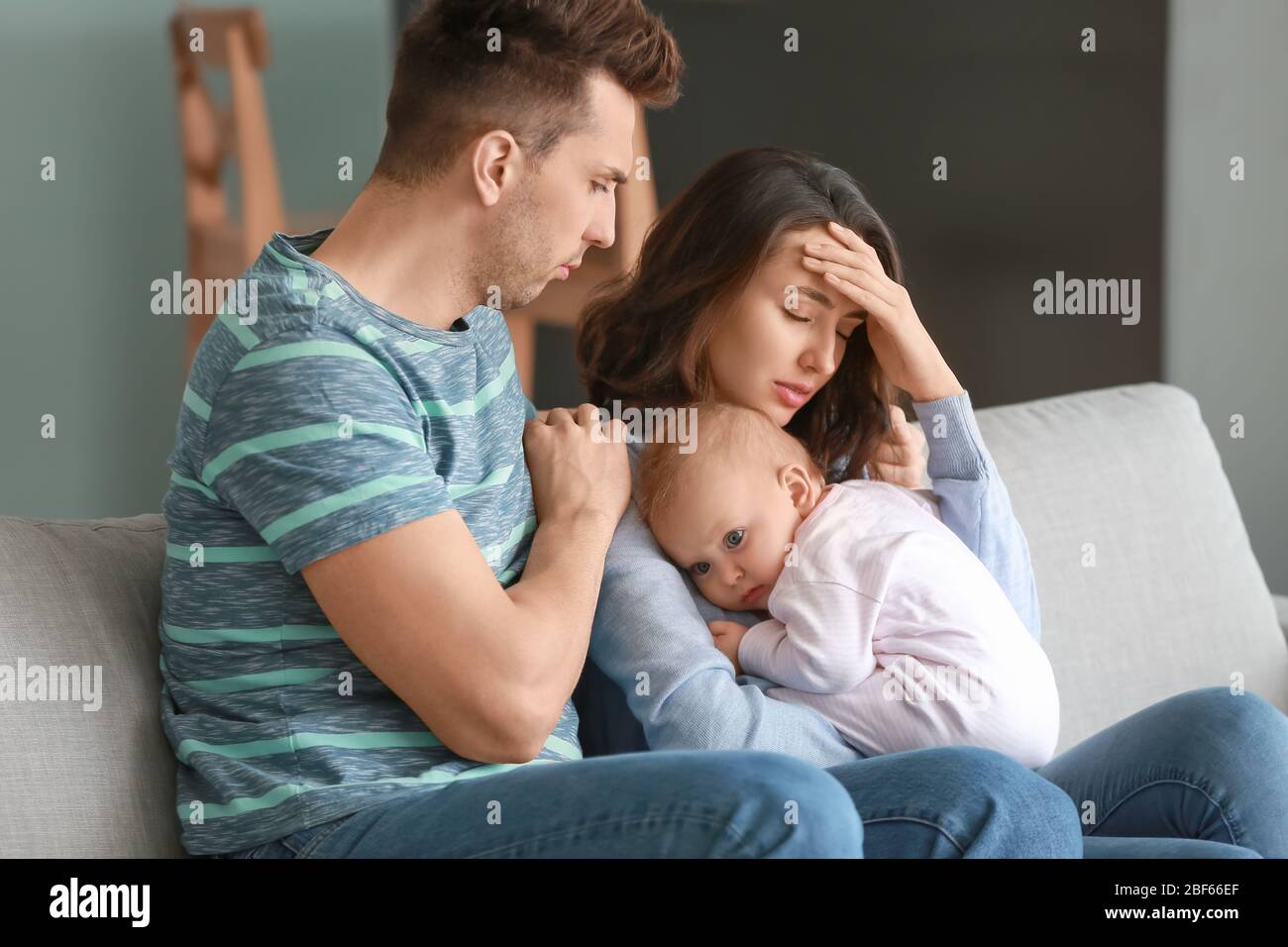 Junger Vater mit Baby und Frau, die zu Hause an postnataler Depression leidet Stockfoto