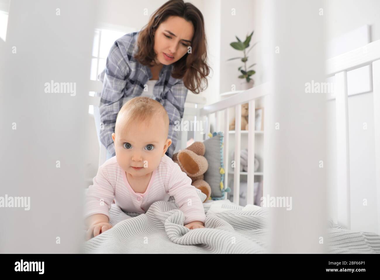 Junge Frau mit postnataler Depression in der Nähe des Bettes mit Baby zu Hause Stockfoto