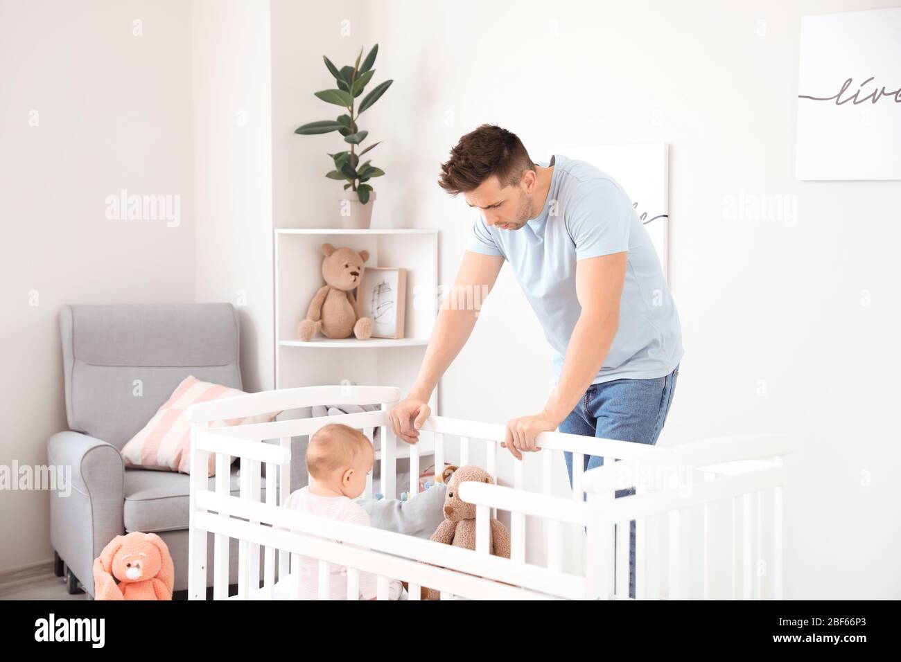 Junger Mann, der an postnataler Depression in der Nähe des Bettes leidet, mit Baby zu Hause Stockfoto