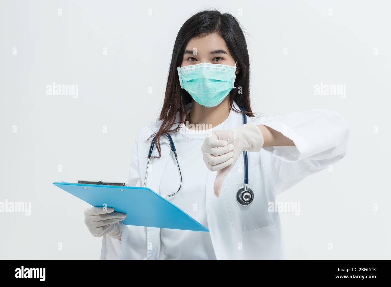 Junge asiatische Arzt Frau trägt Arzt Kleid Uniform Mantel , medizinische Maske und Stethoskop mit einem Clipboard suchen unglücklich und wütend zeigen rejecti Stockfoto