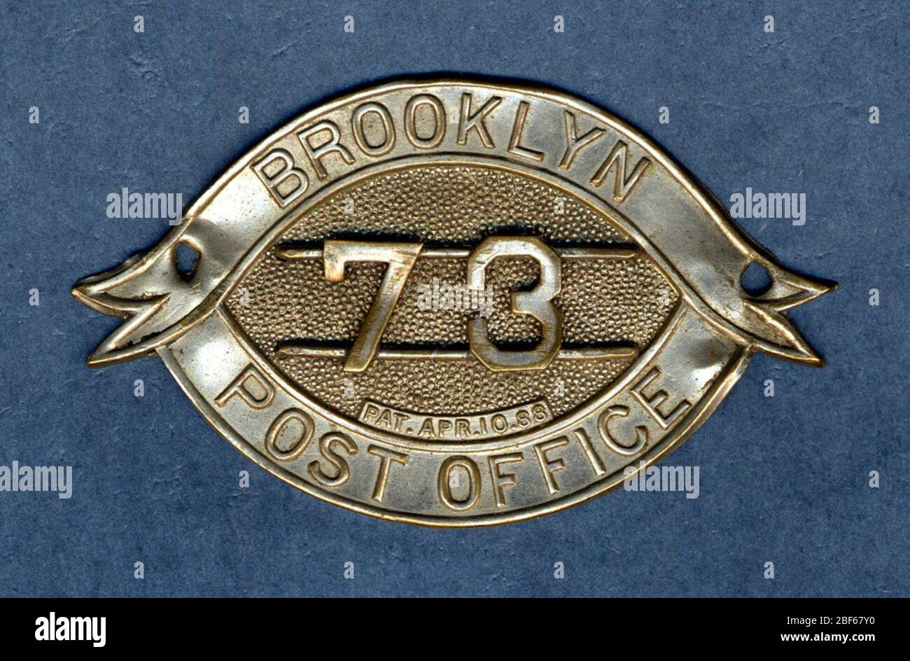 New York Post Office Owney Tag. Owney hat diesen Token möglicherweise von einem Briefträger erhalten. Das Token ist eigentlich eine Kappe Badge Stil von US-Briefträger des späten neunzehnten und frühen zwanzigsten Jahrhunderts getragen. Das Abzeichen ist Nummer 73 von der Brooklyn, New York, Post. Stockfoto