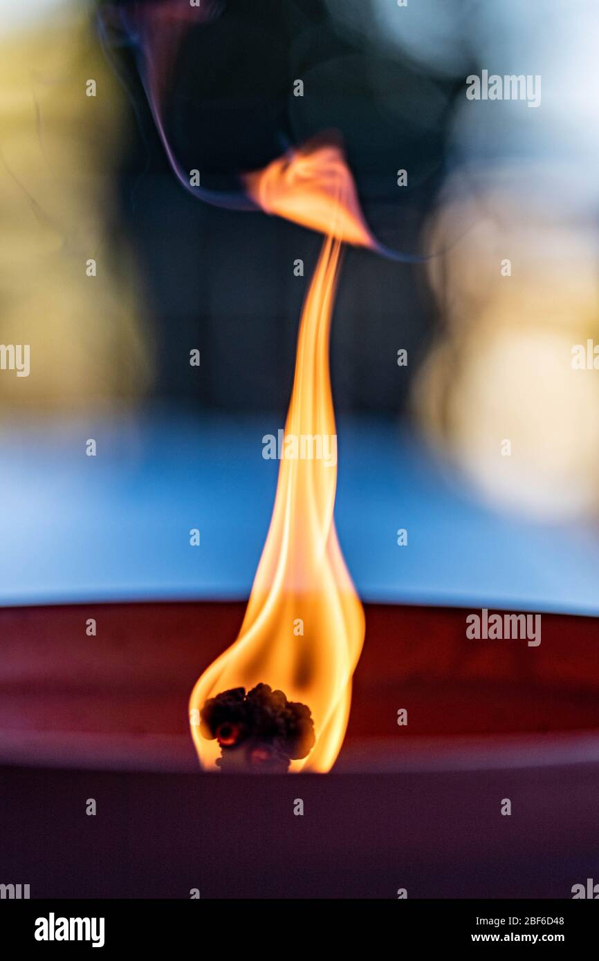 Schwankender Docht einer Mückenbrennenden Kerze, die in einem Tontopf aus Keramik brennt Stockfoto