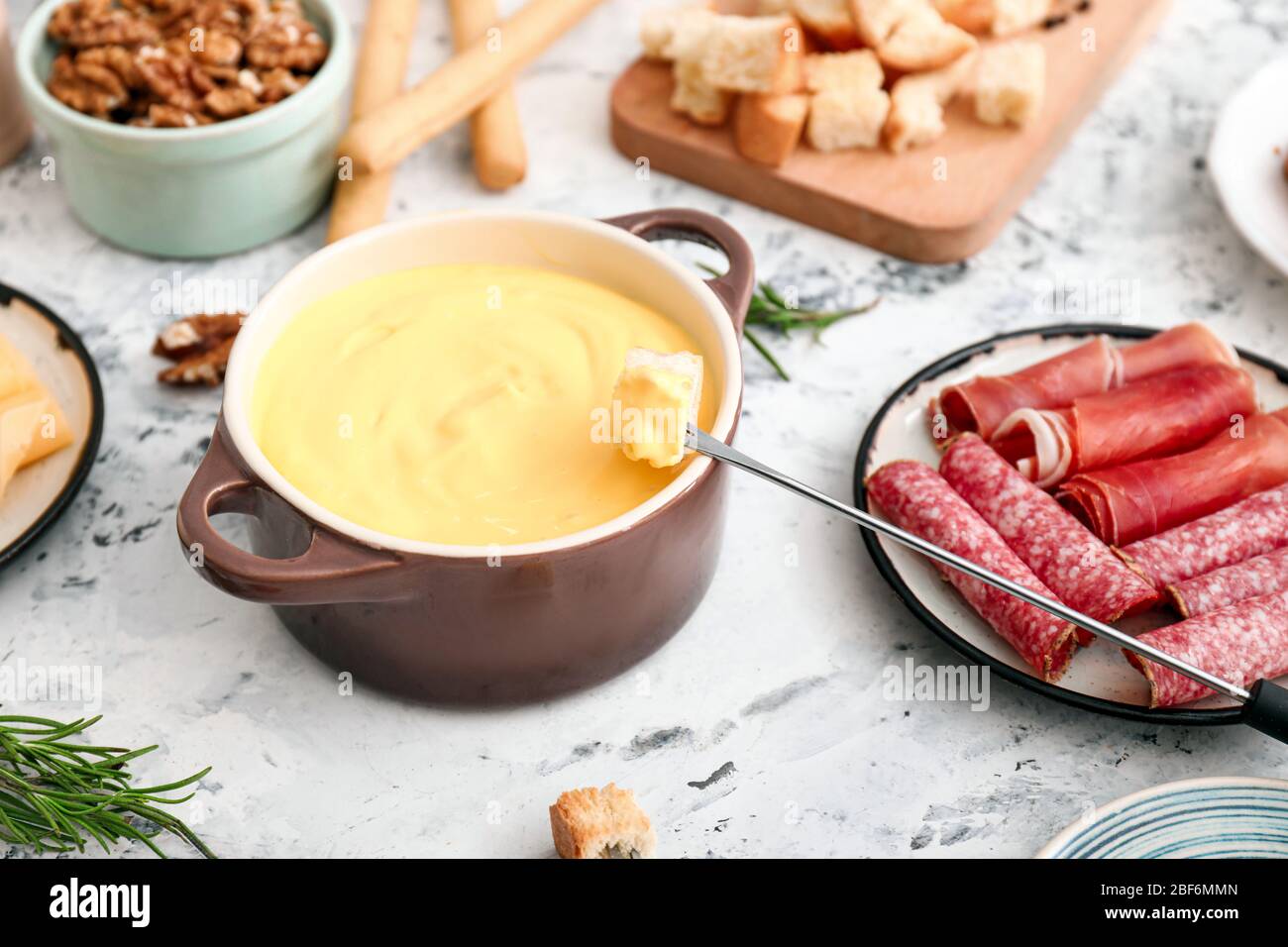 Käsefondue mit Snacks auf weißem Hintergrund Stockfoto