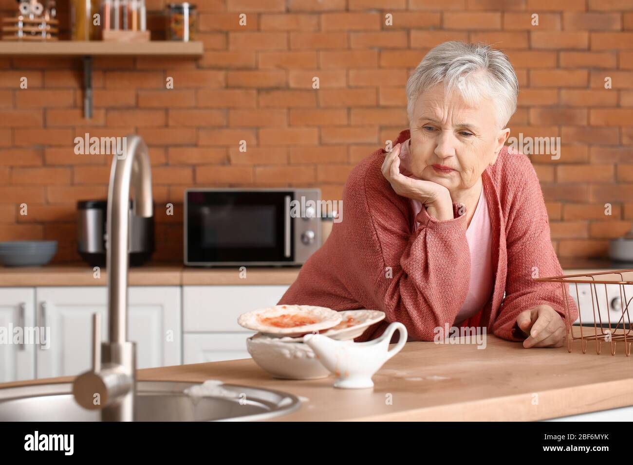 Ältere Frau mit dreckigem Geschirr in der Küche Stockfoto