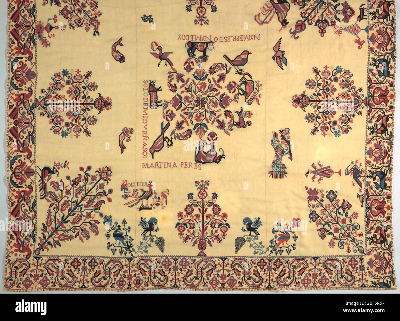 Bettbezug. Cremefarbene Wolle einfarbig mit Wolle in den Farbtönen blau, rot und Lavendel mit etwas gelb bestickt. Stockfoto