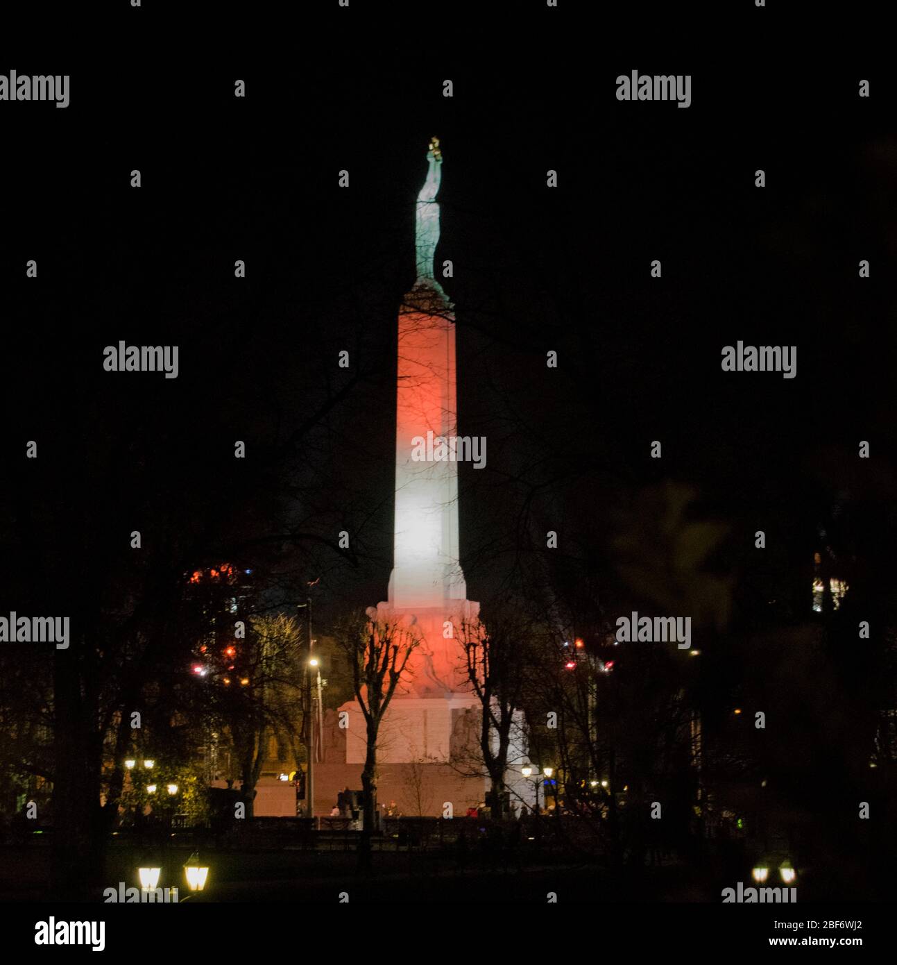 Das Freiheitsdenkmal in Riga, Lettland. Freiheitsstatue mit drei Sternen über der Stadt in verschiedenen Farben beleuchtet. Stockfoto