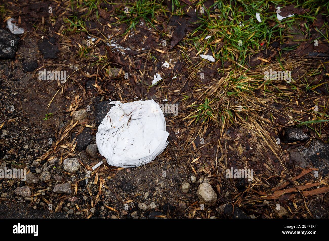 Einweg-Plastikgeschirr sind lange im Wald gelassen worden. Weiße Plastikpantoffeln, Gabeln werden auf den Boden geworfen. Müll im Wald. Das Problem der Verschmutzung von Plastikmüll. Stockfoto