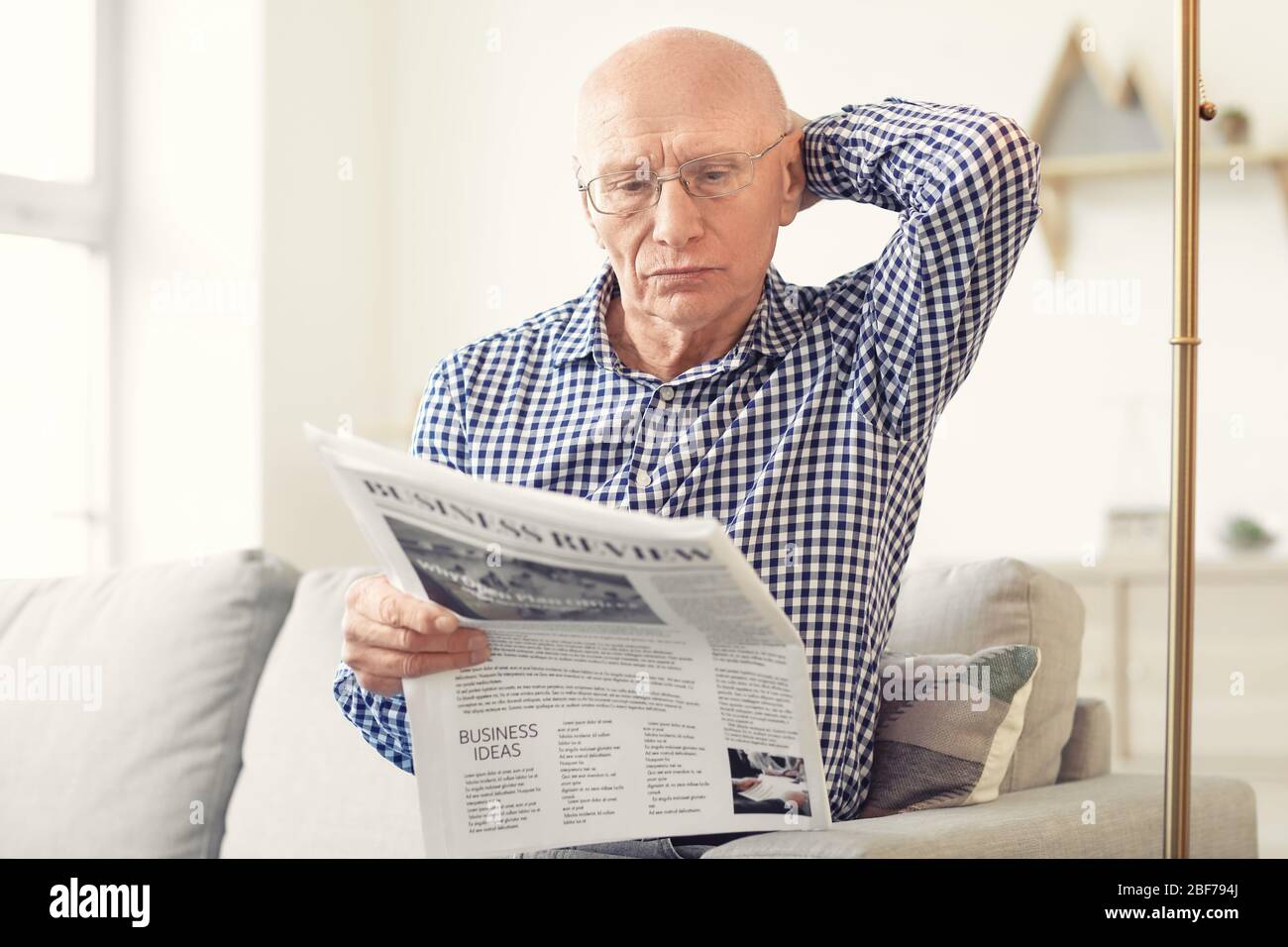 Älterer Mann liest Zeitung zu Hause Stockfoto