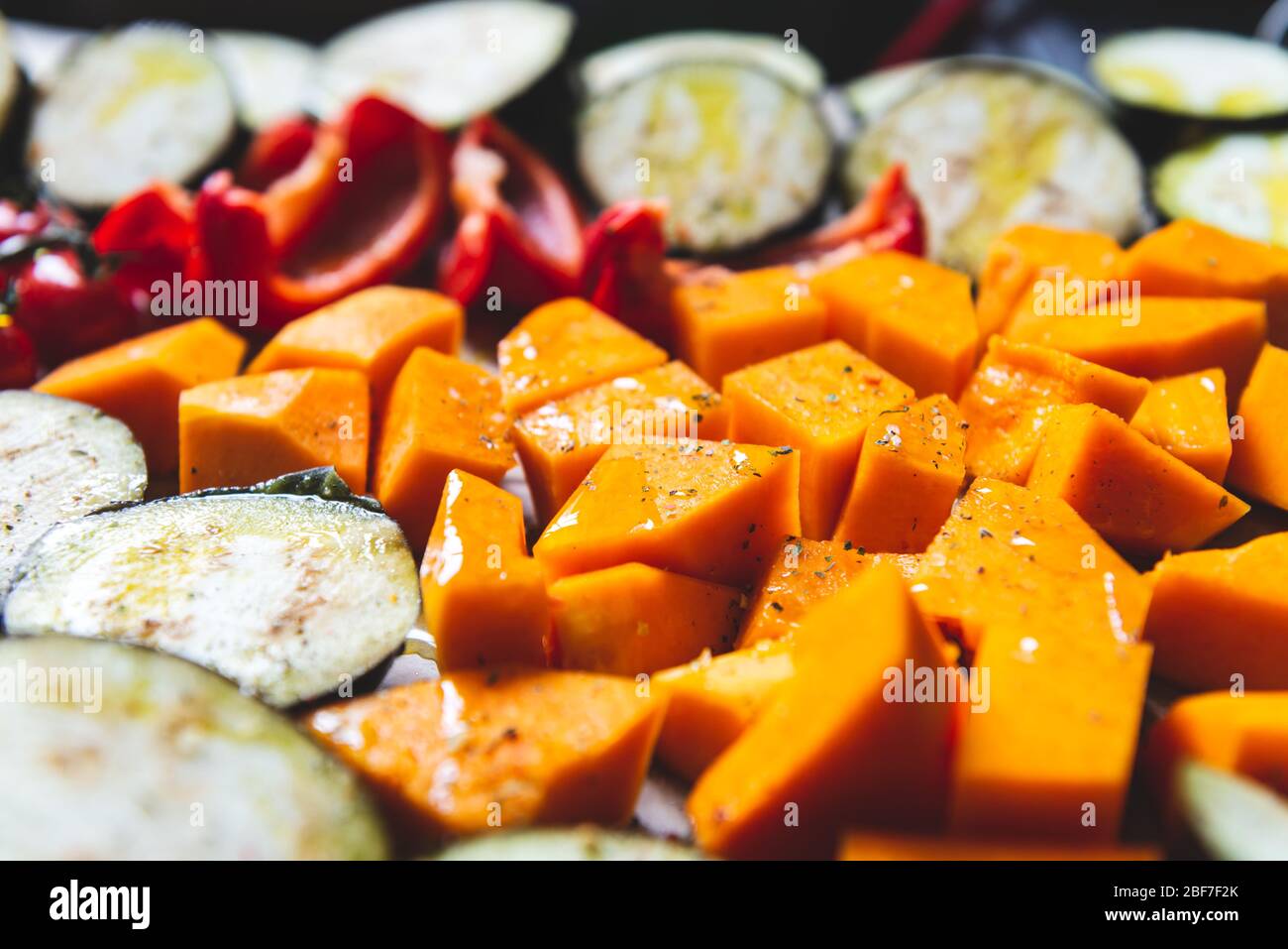 Gesundes Detox-Abendessen aus verschiedenen Gemüsesorten wie Aubergine, roter Pfeffer, Kirschtomaten, Butternusskürbis. Scheiben rohes Gemüse, das für das Braten vorbereitet wird, einfache Familienmahlzeit Stockfoto