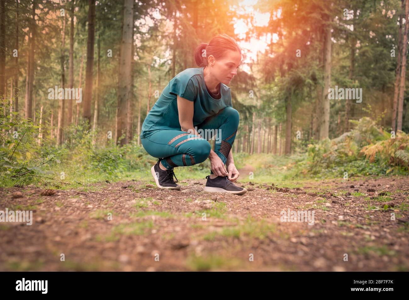 Frau Läufer tun ihre Schnürsenkel bis, im Freien im Wald. Stockfoto
