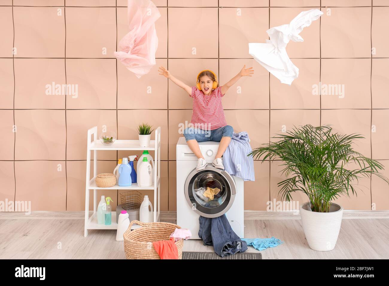 Kleine Hausfrau hört Musik in der Waschküche Stockfoto