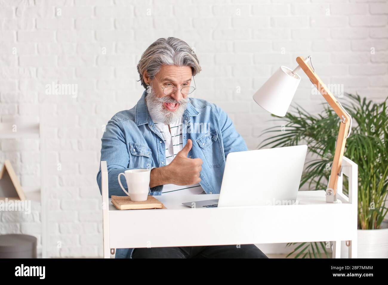 Emotional älterer Mann mit Laptop im Büro Stockfoto