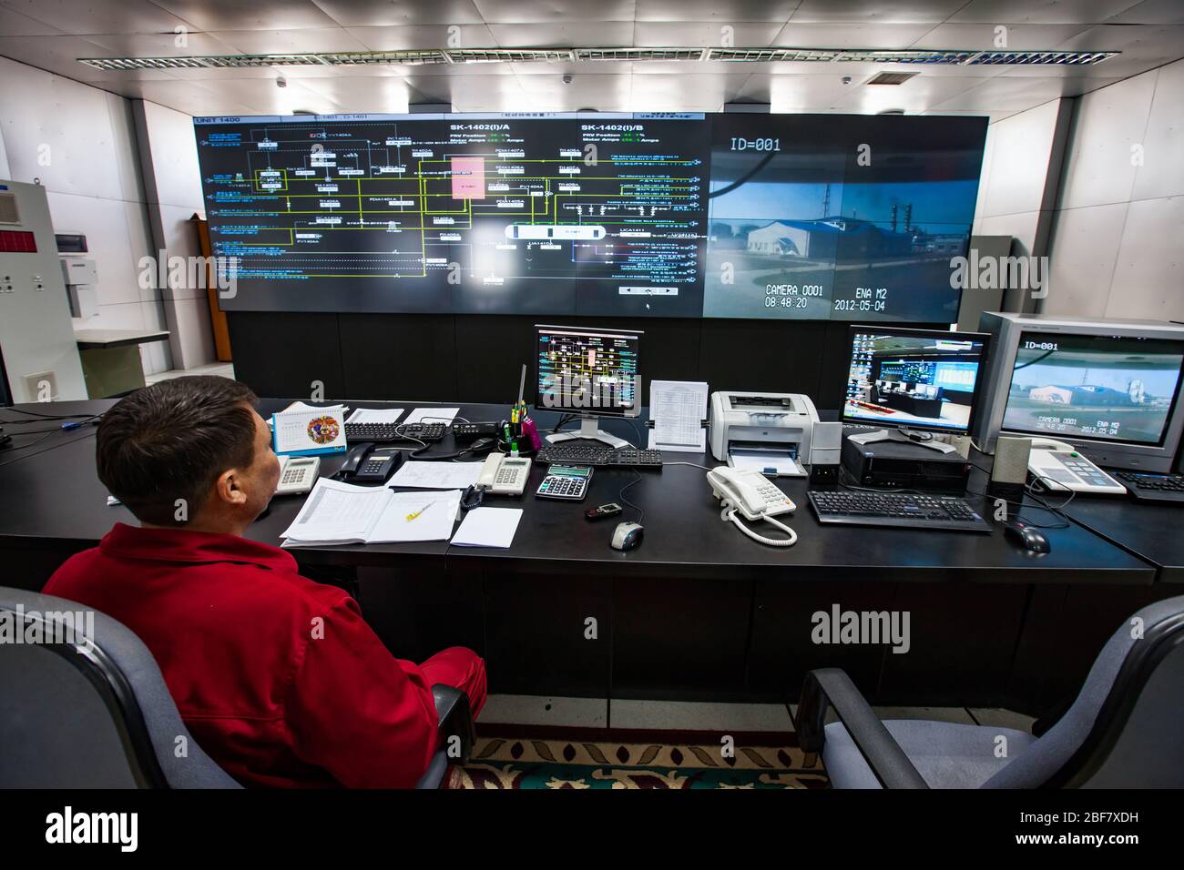 Ölraffinerie-Werk. Operational Control Center (Kontrollraum). Bediener bei der Überwachung des roten Arbeitsverschleißes. CNPC-Unternehmen. Stockfoto
