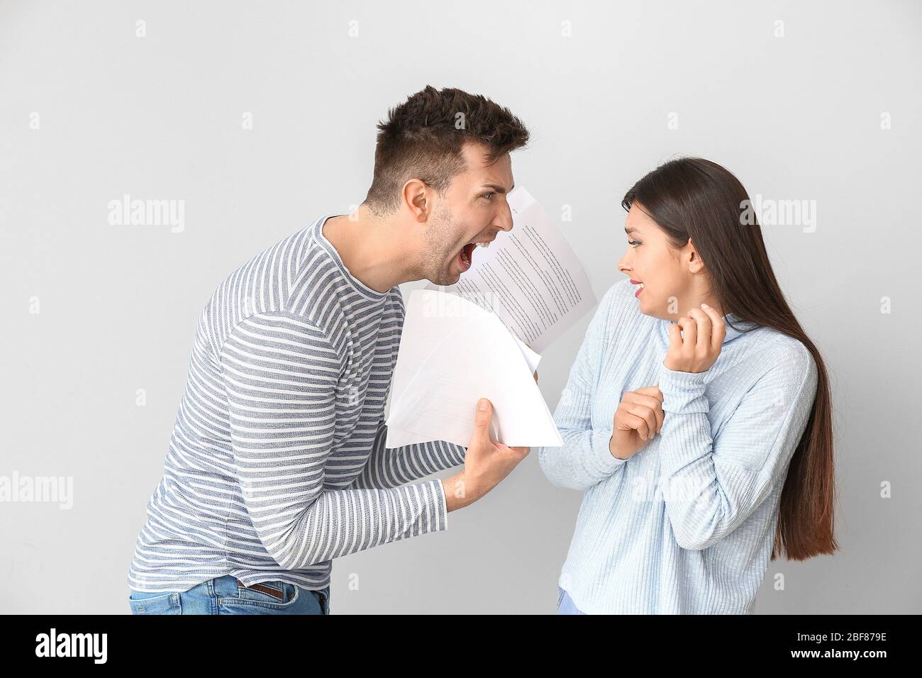 Missfiel Mann schimpft seine Frau für zu viel auf hellen Hintergrund Stockfoto