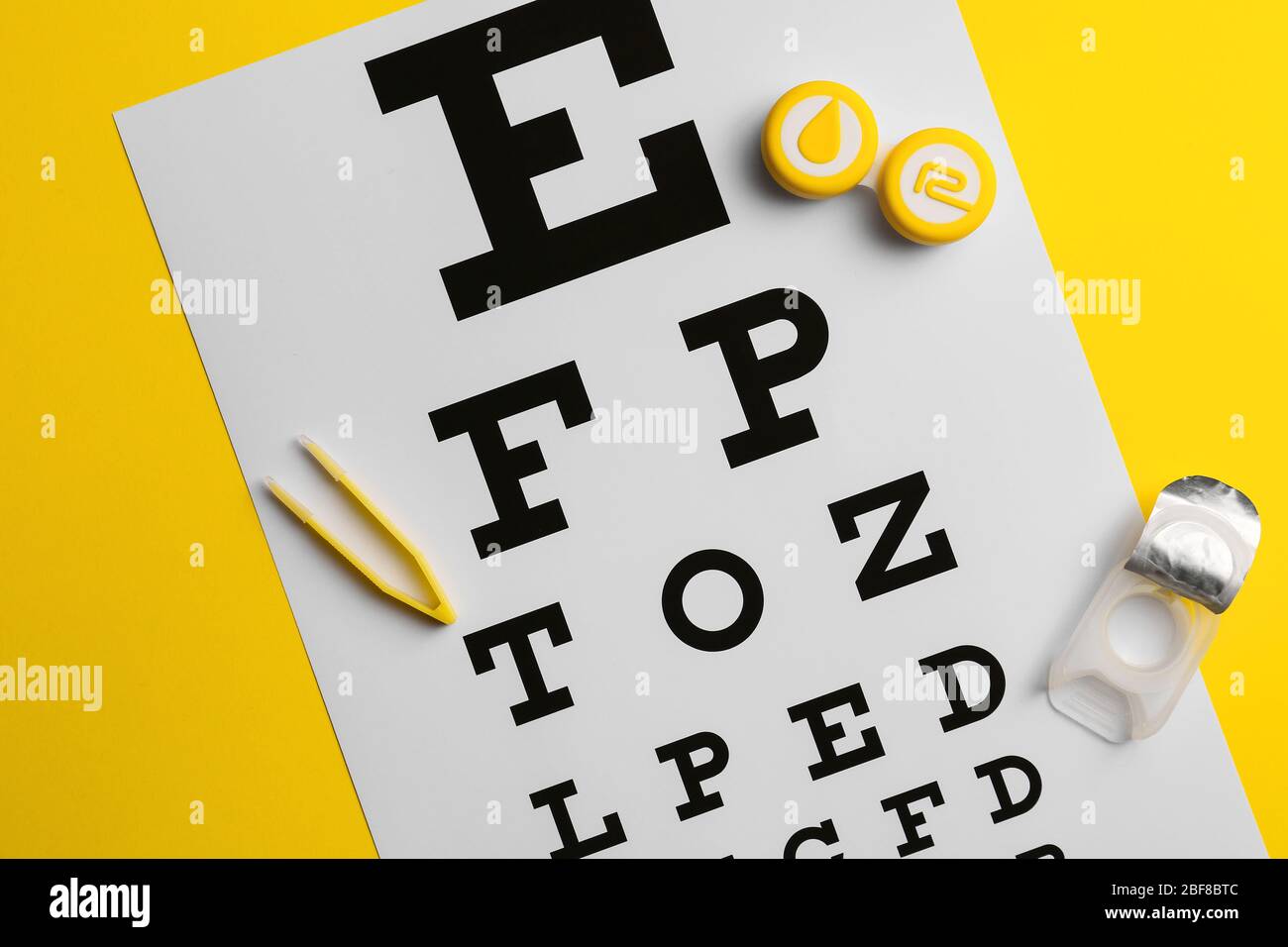 Behälter mit Kontaktlinsen, Pinzette und Augentestkarte auf farbigem Hintergrund Stockfoto