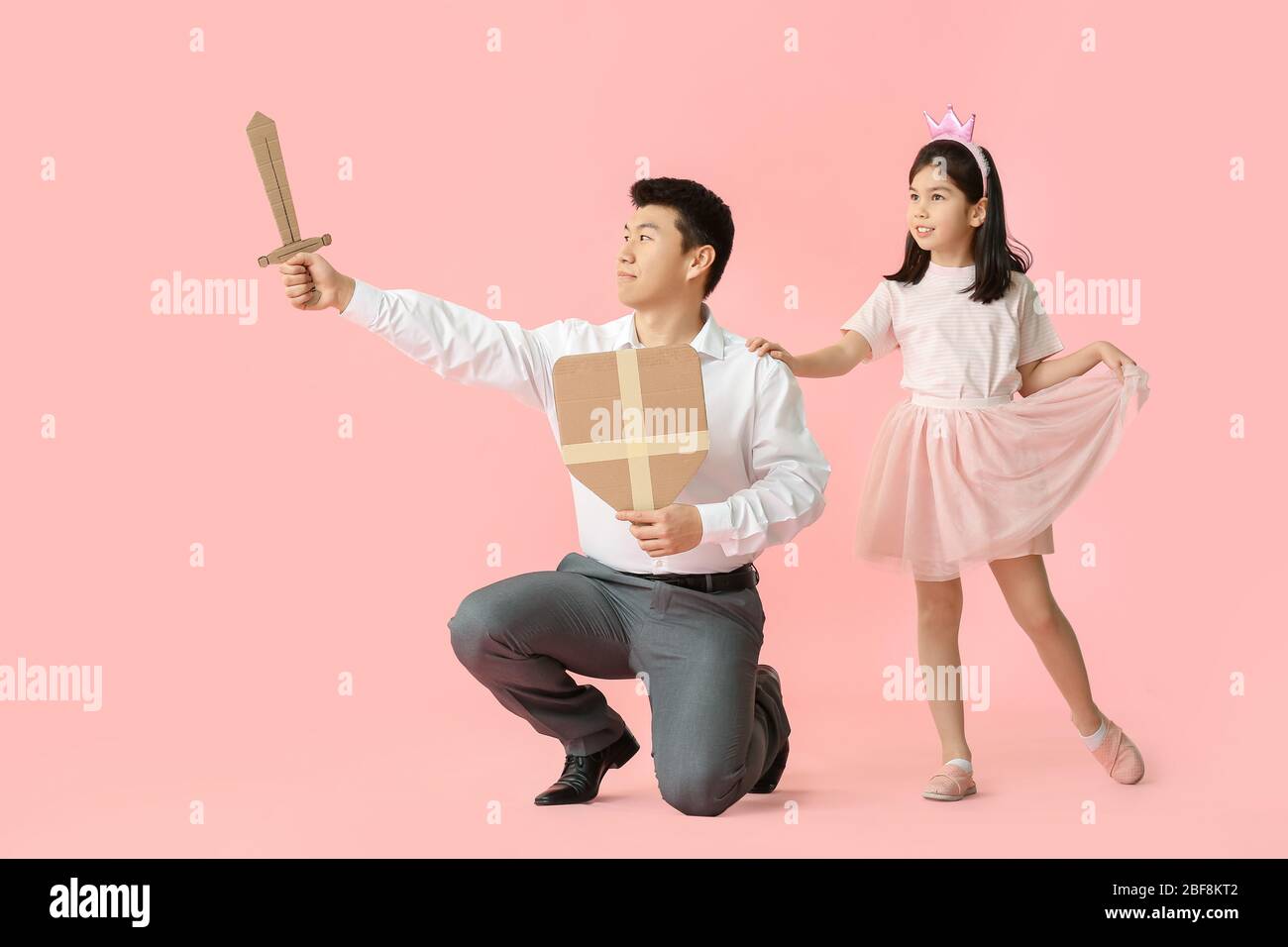 Asian Mann und seine kleine Tochter als Prinz und Prinzessin auf farbigen Hintergrund gekleidet Stockfoto