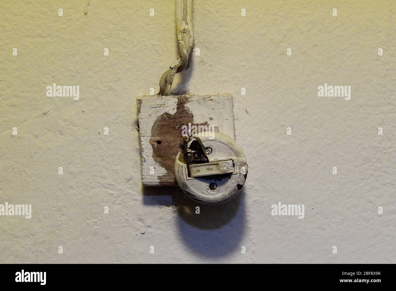 Alter defekter Lichtschalter mit freiliegenden Drähten. Stockfoto
