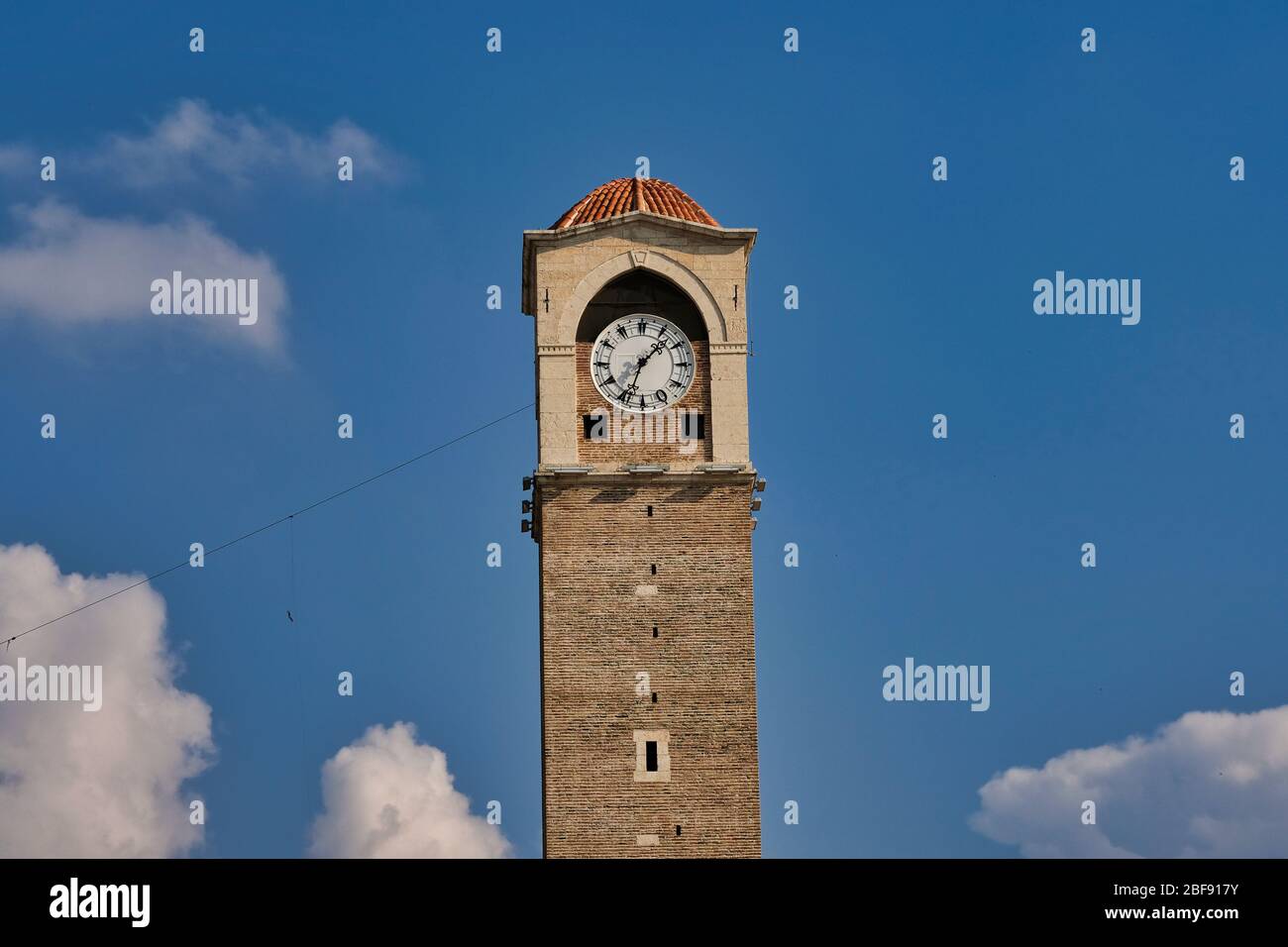 Alter Uhrenturm mit blauem und wolkenverstrahlten Himmel in Adana, Türkei. Historischer alter Uhrenturm namens 'Büyüksaat' Stockfoto