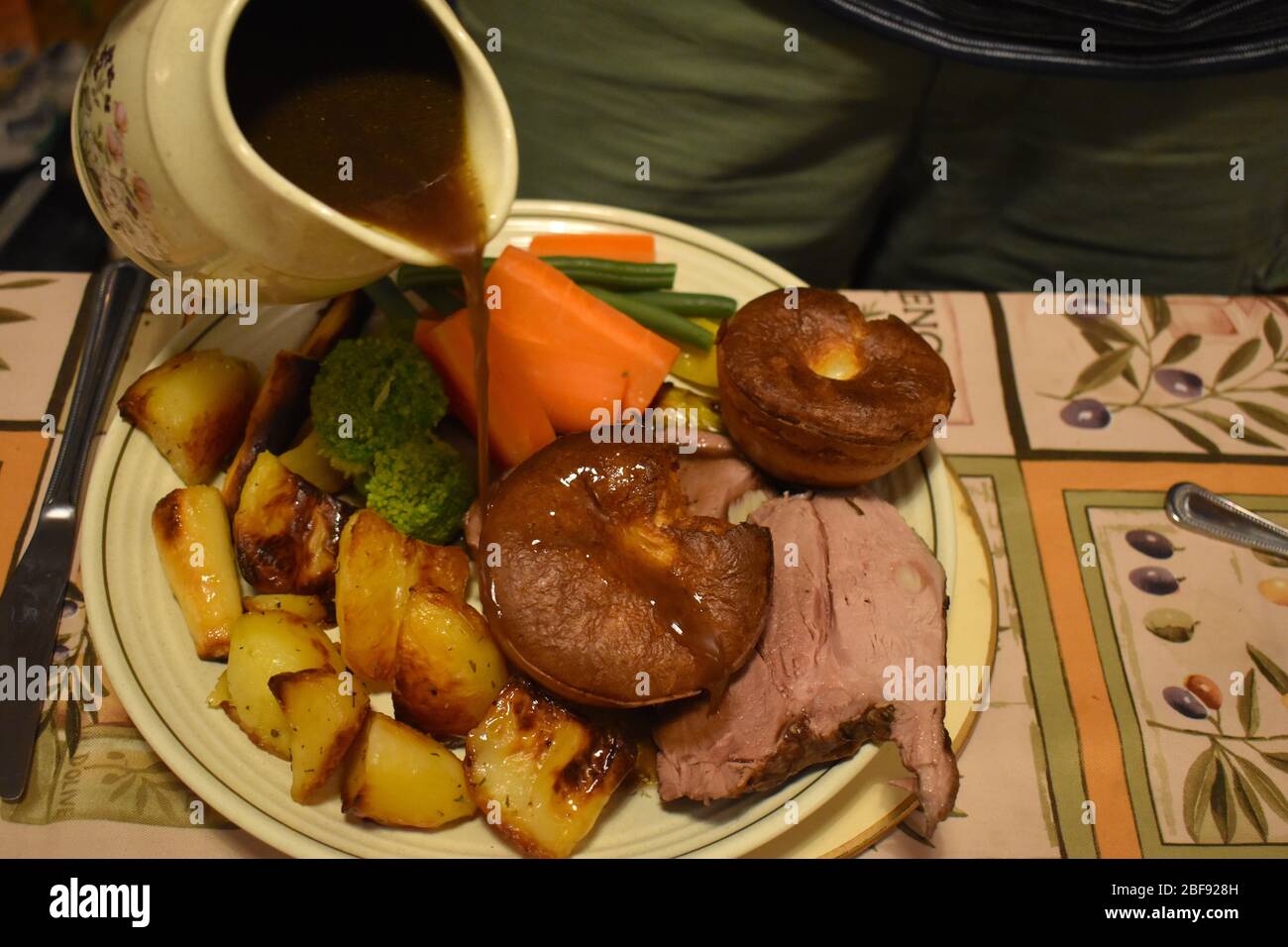 Lammsoße auf Sonntagsbraten gegossen. Rotwein und Mehl verdicken Fleisch Säfte Abendessen einschließlich Yorkshire Pudding Kartoffeln Lauch Pastinaken grüne Bohnen Stockfoto