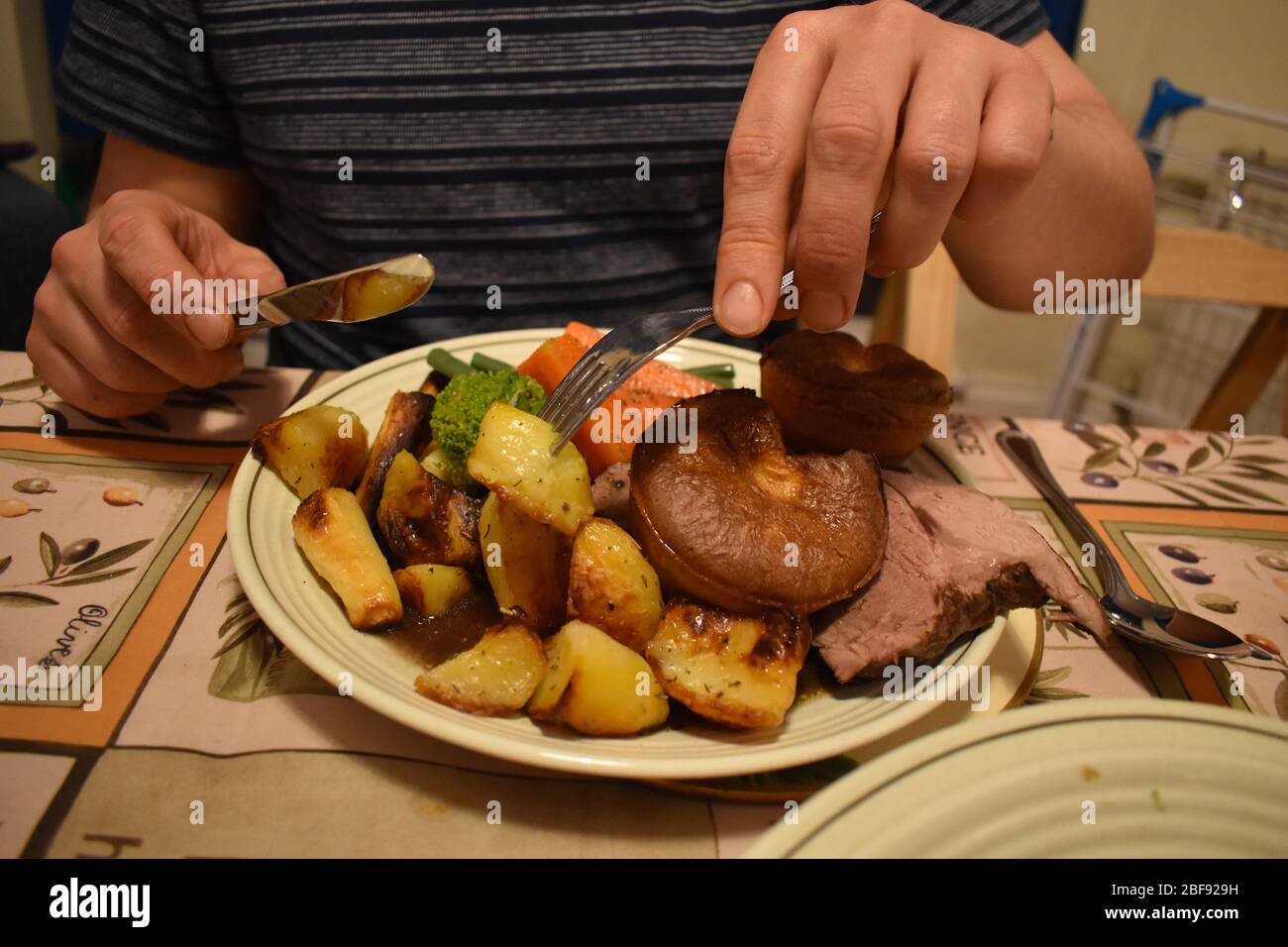 Mann, der am Sonntag Lammbraten gegessen hat. Teller voller Kartoffeln Lauch Karotten Brokkoli Yorkshire Pudding geschnitzte Fleisch grüne Bohnen. Traditionelle britische Küche Stockfoto