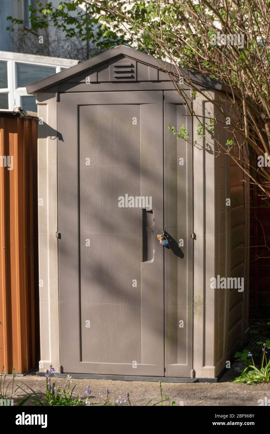 Eine Nahaufnahme eines Plastikschuppens oder einer Lagereinheit, die im kleinen Garten ein kleines Schloss hat Stockfoto