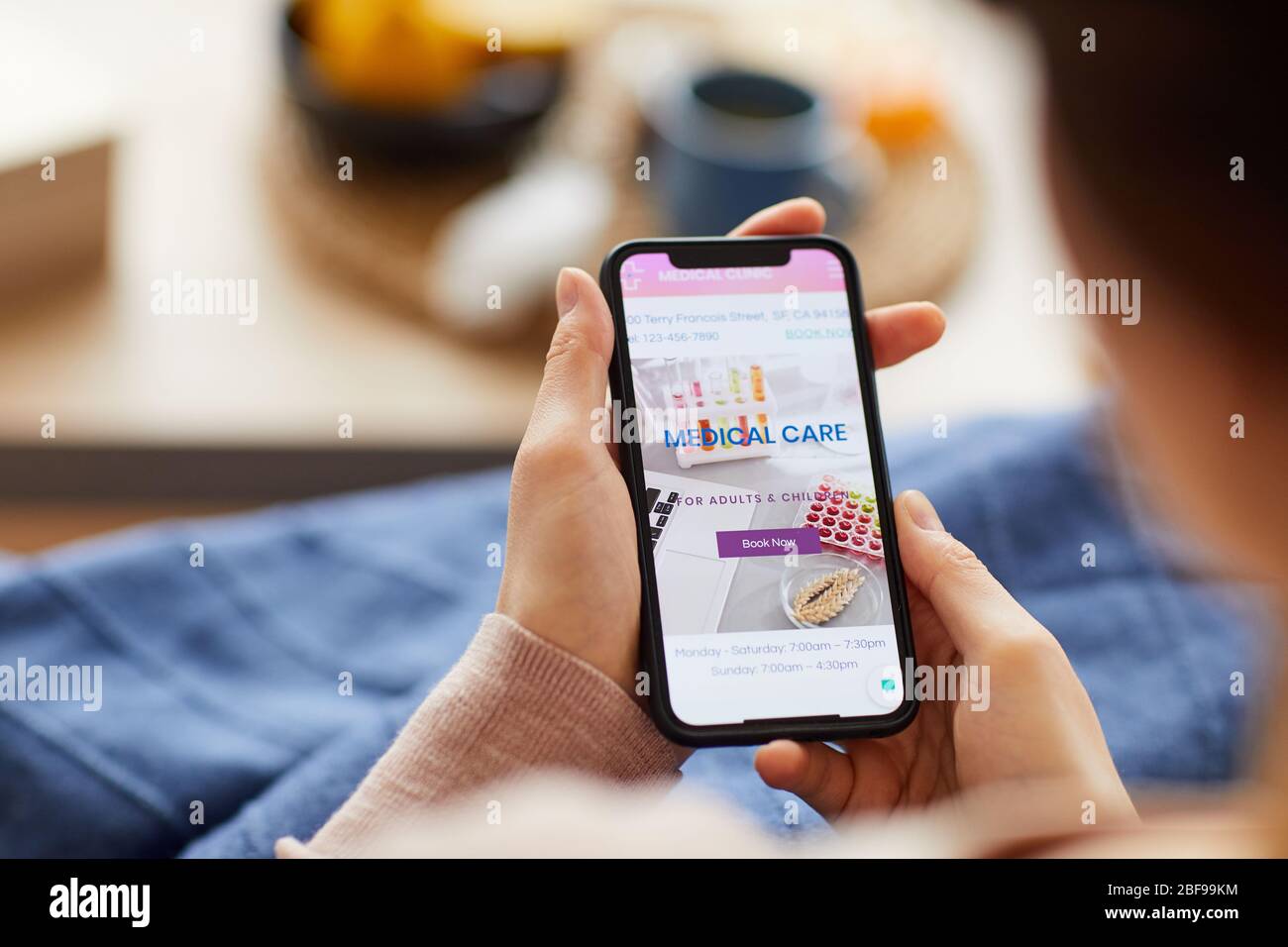 Nahaufnahme einer Frau, die auf dem Sofa sitzt und medizinische Anwendungen auf ihrem Mobiltelefon zu Hause verwendet Stockfoto