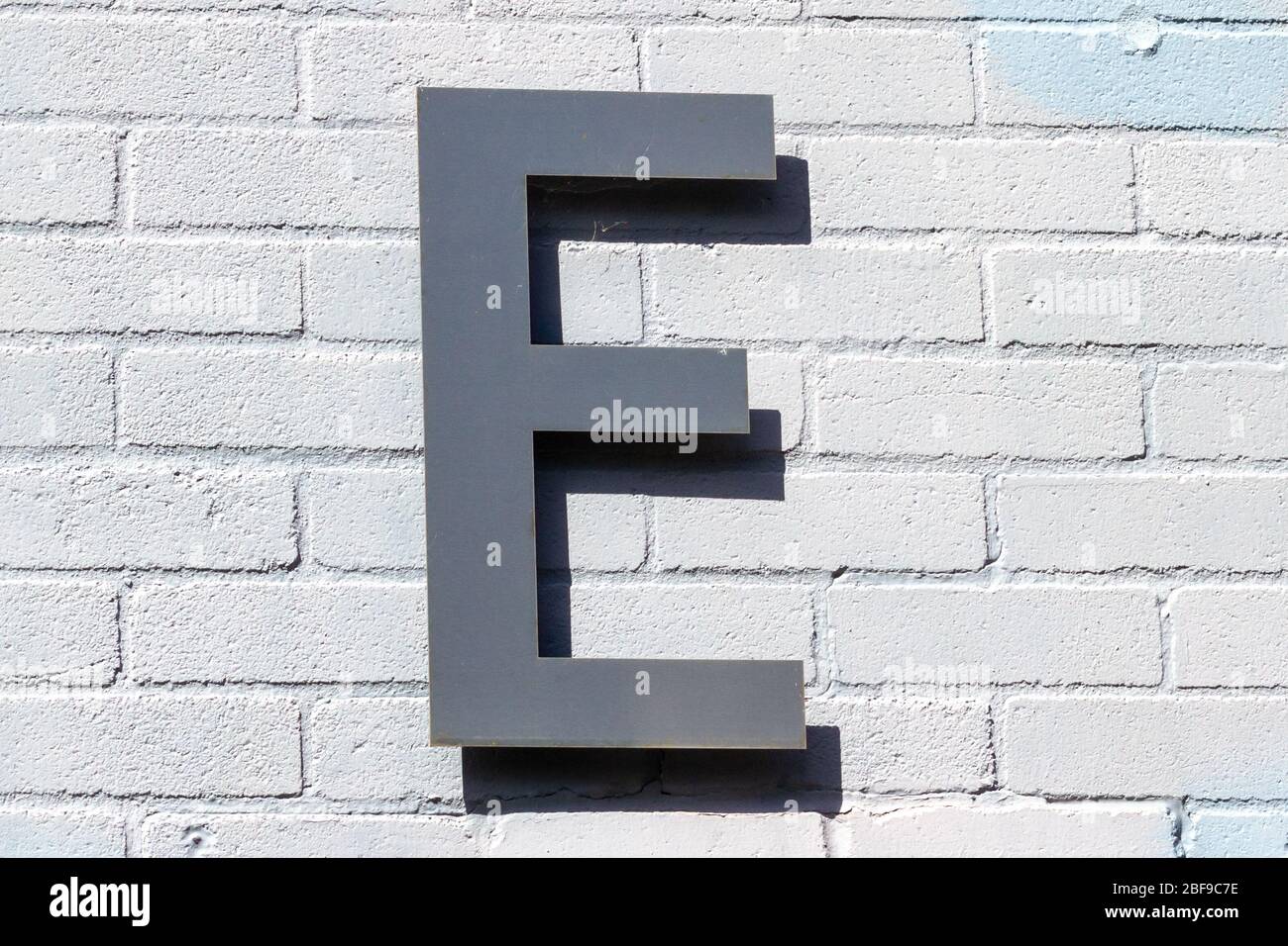Der Buchstabe E als Großbuchstabe auf einer weißen Ziegelwand Stockfoto