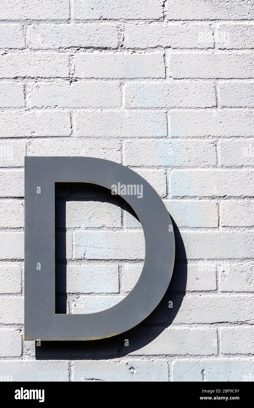 Der Buchstabe D als Großbuchstabe auf einer weißen Ziegelwand Stockfoto