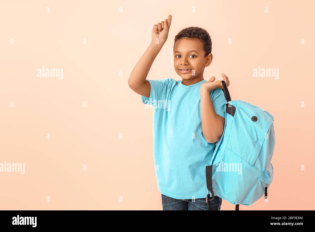 Niedlichen afroamerikanischen Schuljungen mit erhöhten Zeigefinger auf farbigen Hintergrund Stockfoto