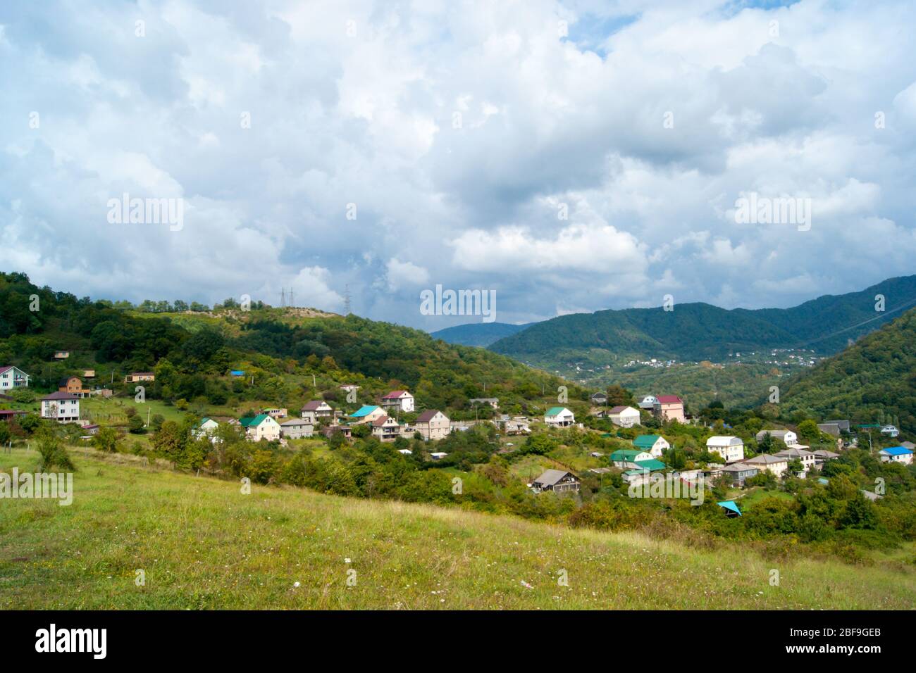 Horizontale Foto - Sommer Berglandschaft. Bergdörfer, Domius mit farbigen Dächern gegen den grünen und blauen Himmel in weißen Wolken. Stockfoto