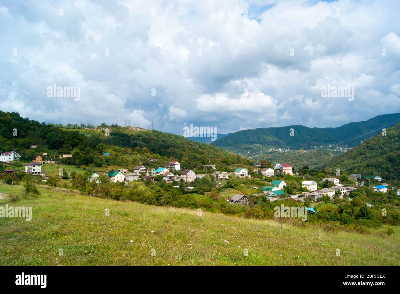 Horizontale Foto - Sommer Berglandschaft. Bergdörfer, Domius mit farbigen Dächern gegen den grünen und blauen Himmel in weißen Wolken. Stockfoto