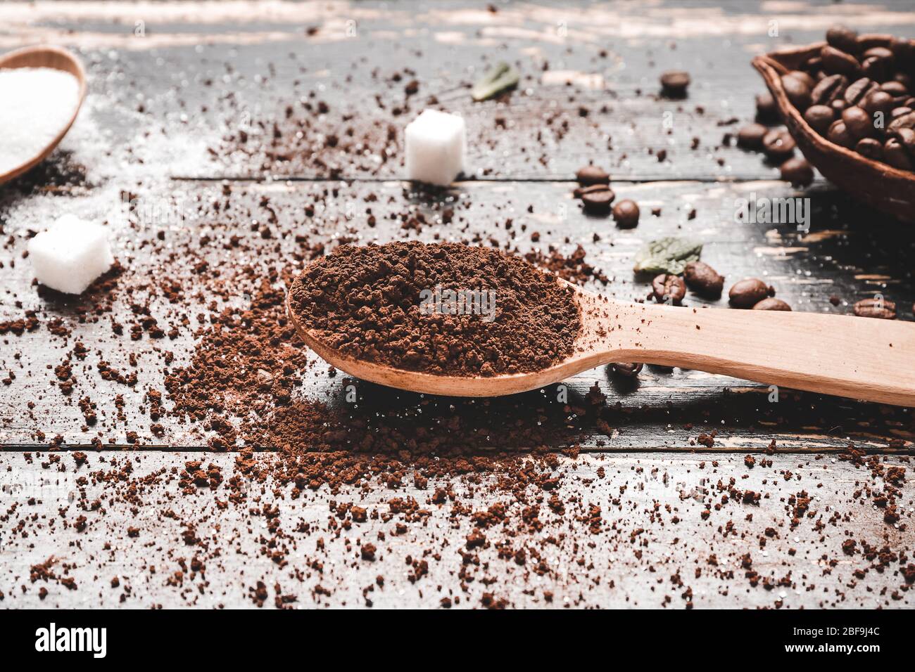Löffel mit gemahlenem Kaffee und Bohnen auf Holzhintergrund Stockfoto