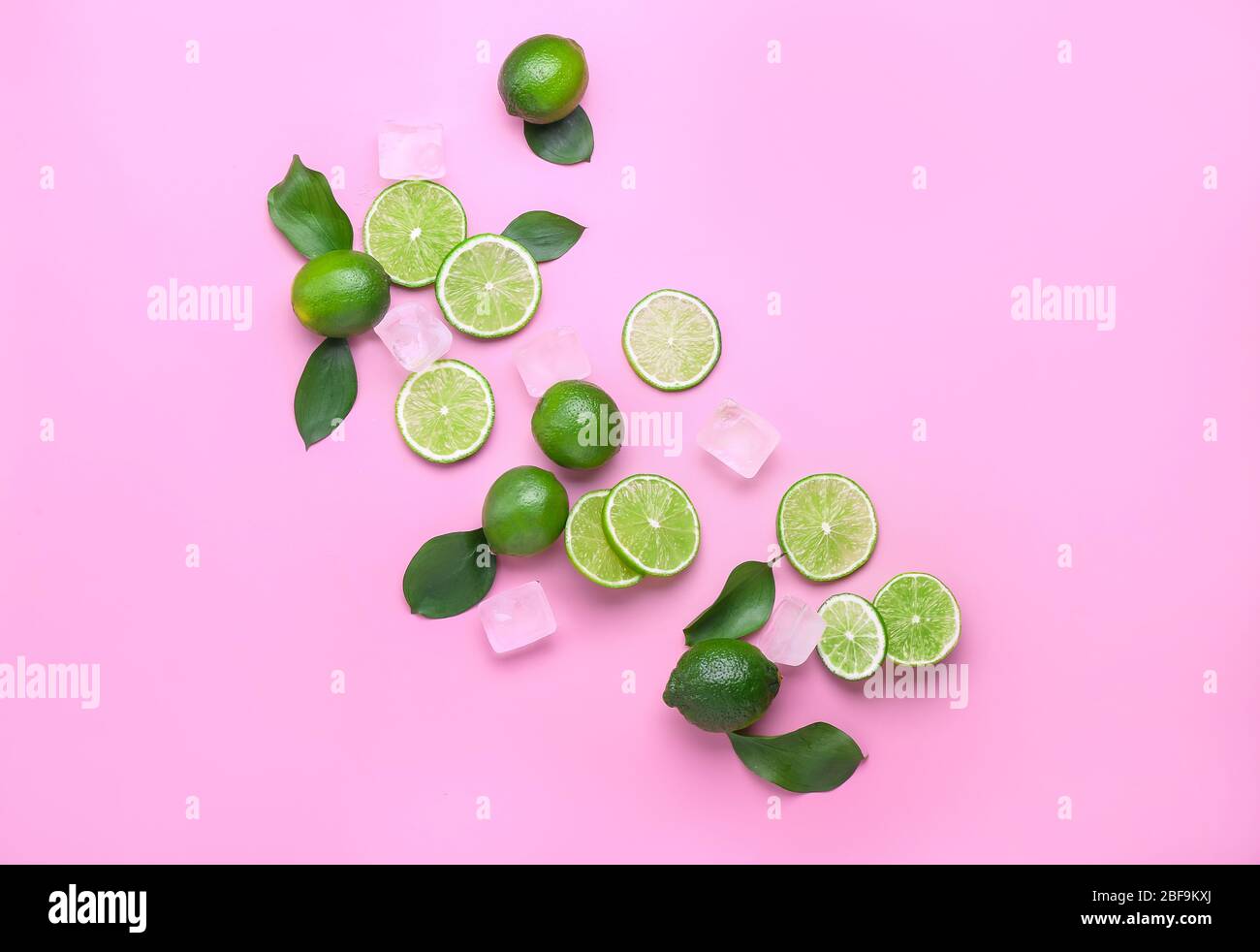 Frische Limetten und Eiswürfel auf farbigem Hintergrund Stockfoto