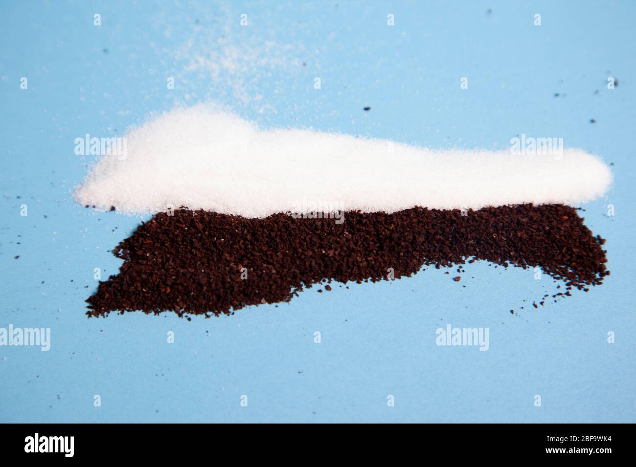 Brauner Kaffee mahlt mit weißem Zuckergranulat vor blauem Hintergrund Stockfoto