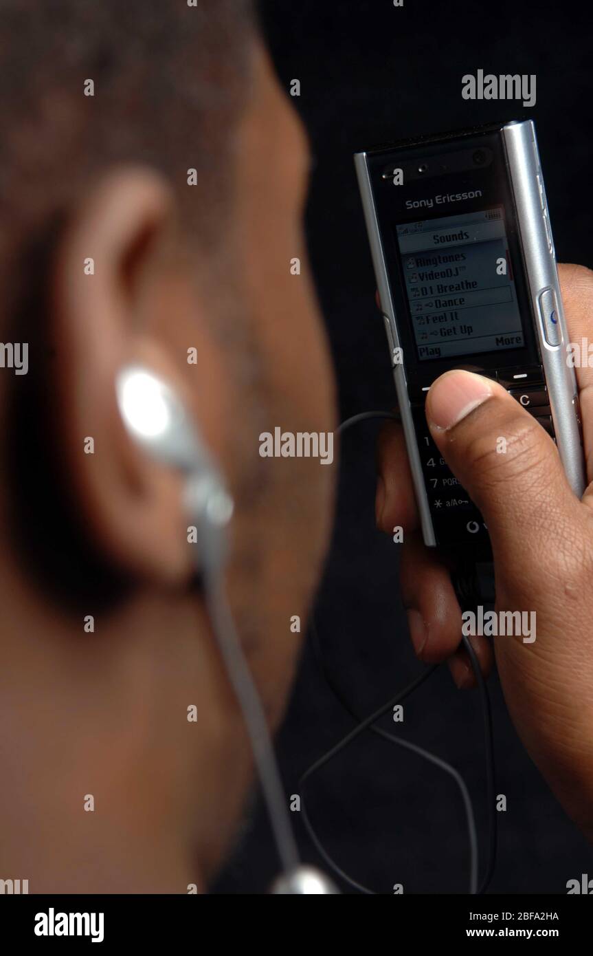 Mann, der das Mobiltelefon von Sony Ericsson verwendet, um Musik zu hören. Stockfoto