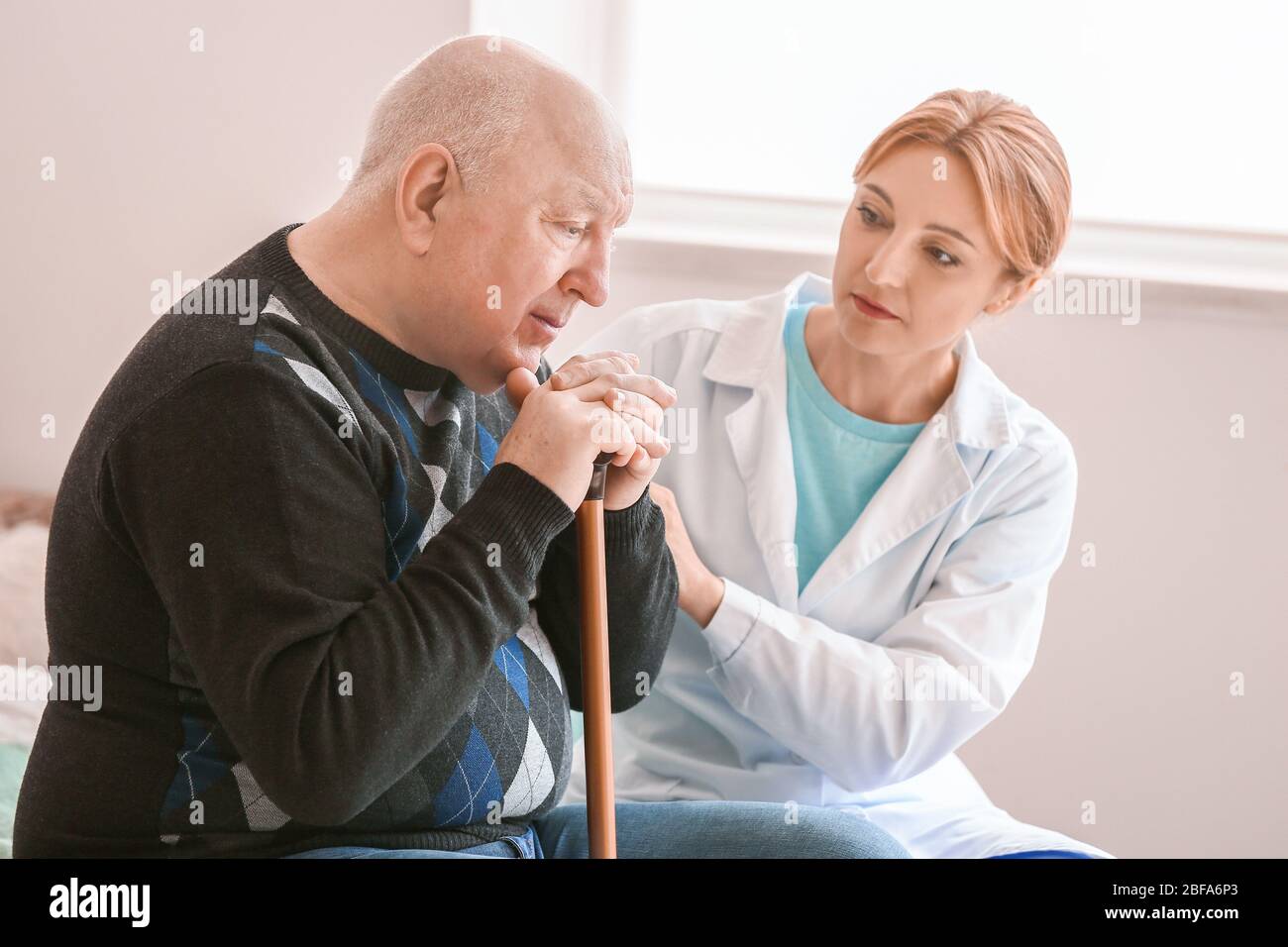 Älterer Mann mit geistiger Behinderung und Arzt zu Hause Stockfoto