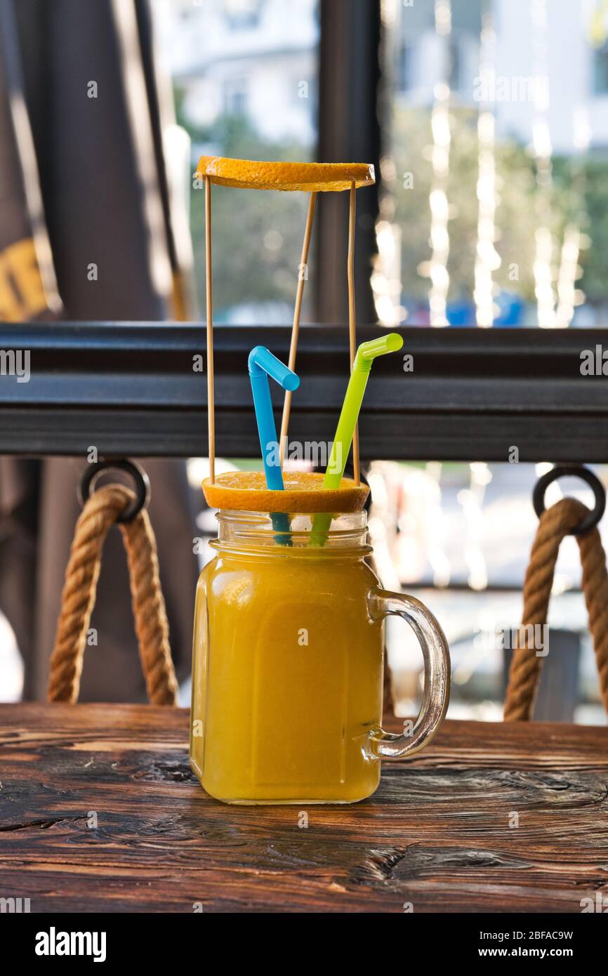 Frisch gepresster Bio-Orangensaft. Speziell gearbeiteter Orangensaft. Exotische alkoholische Cocktails auf einem Holztisch. Orange und gelb rosa weich Stockfoto
