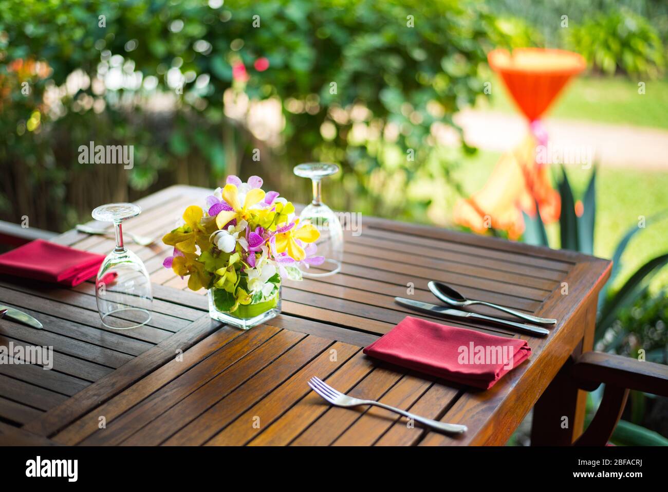 Farbenfrohes, wunderschönes Orchideen-Bouquet-Dekor in Glasvase, eingerichtet auf einem Holz-Esstisch in Indien, Empfang für Hochzeitsfeiern. Stockfoto