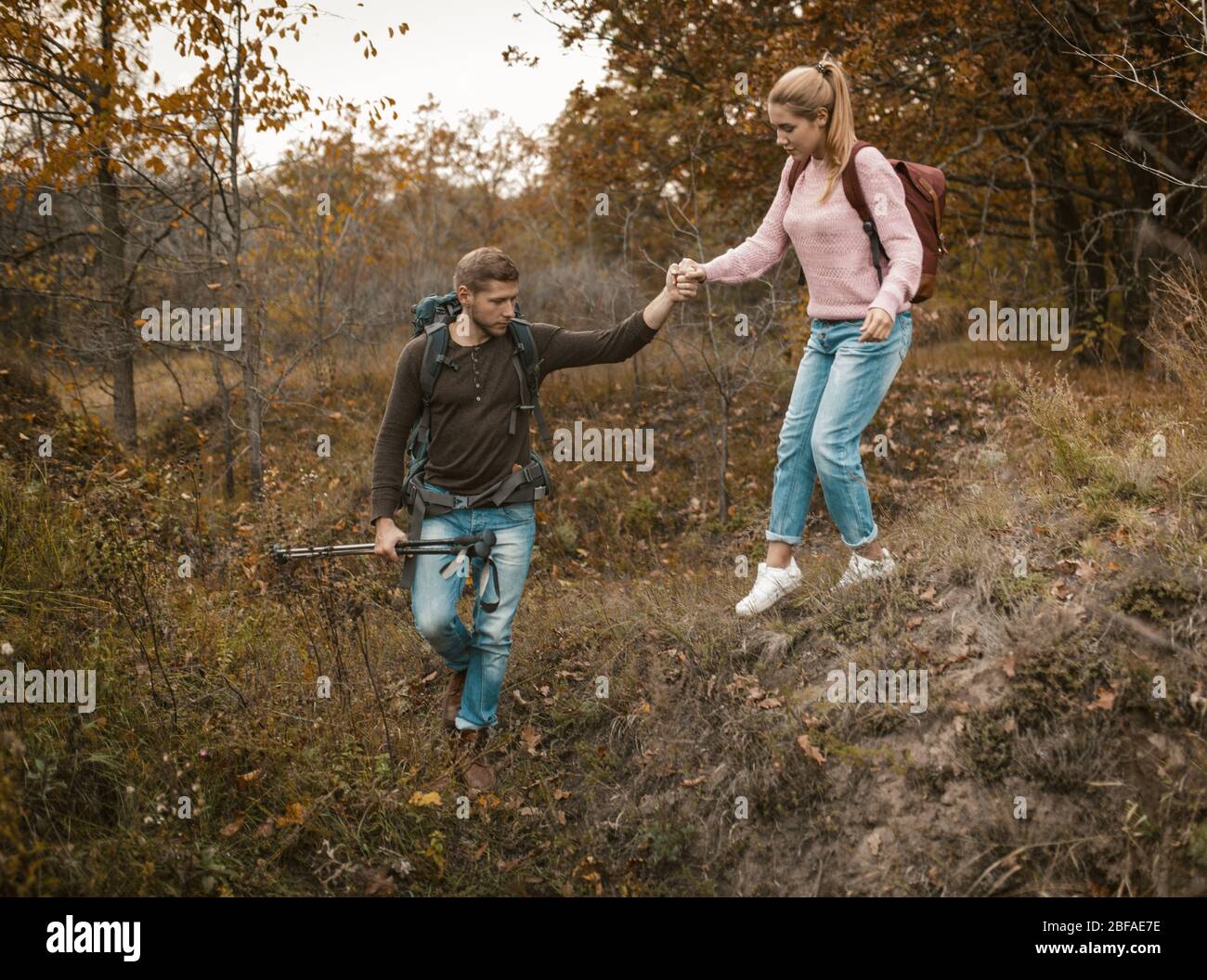 Mann Unterstützt Frau, Um Den Hügel Hinunter Im Freien Zu Gehen Stockfoto