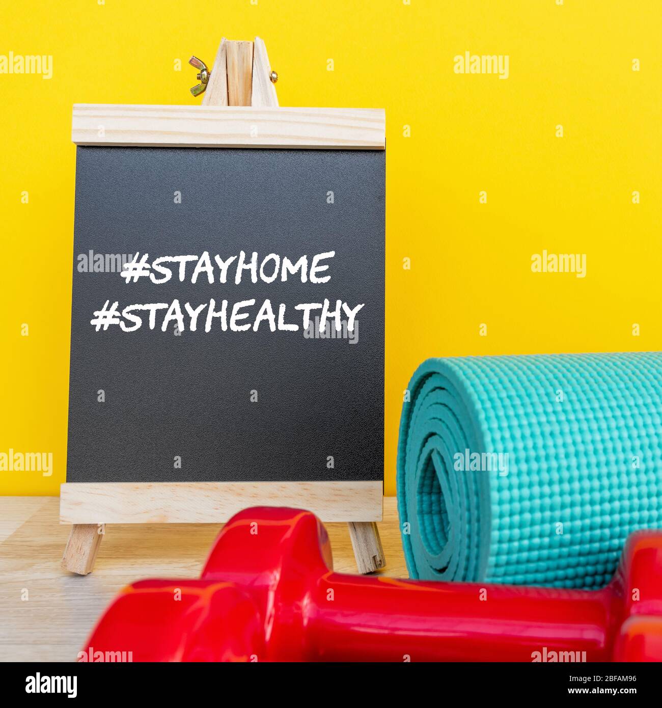 Gesund bleiben während des Aufenthalts zu Hause Auftragskonzept - Tafel, Hantel und Yoga-Matte. Stockfoto