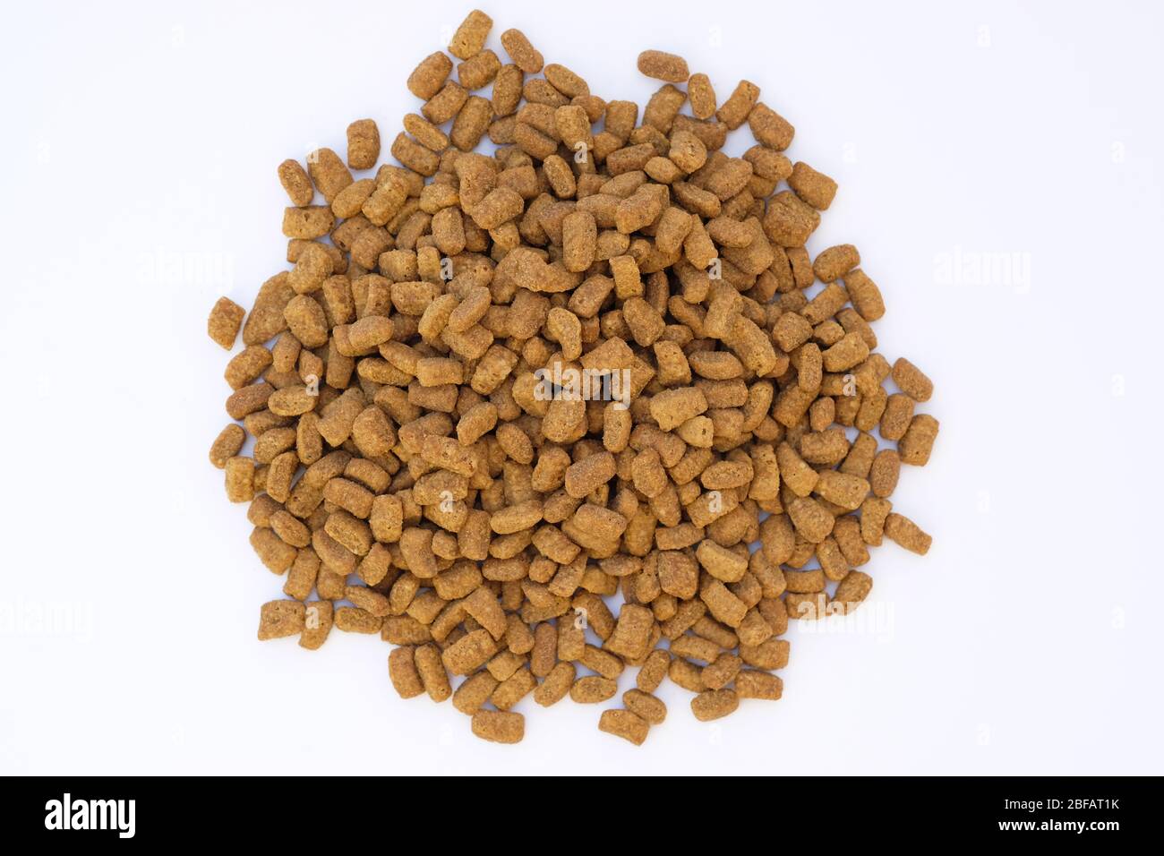 Trockenes Katzenfutter auf weißem Hintergrund. Braune Körnchen von Trockenfutter für Erwachsene sterilisierte Katzen. Kleine Granulate mit putengeschmack Futter für Hauskatzen. Stockfoto