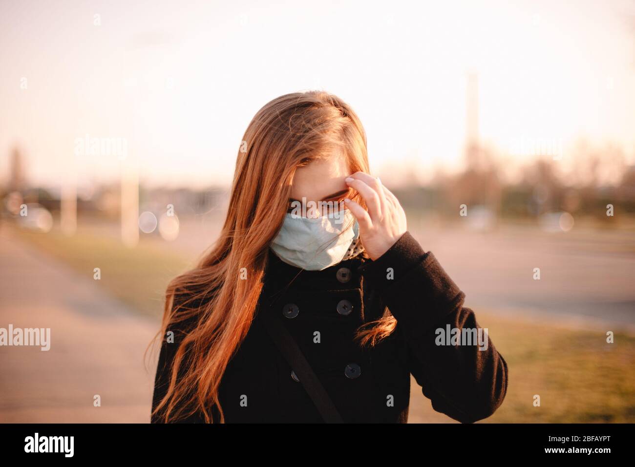 Porträt einer jungen Frau mit Schutzmaske Gesicht medizinische Maske beim Gehen auf der Straße in der Stadt Stockfoto